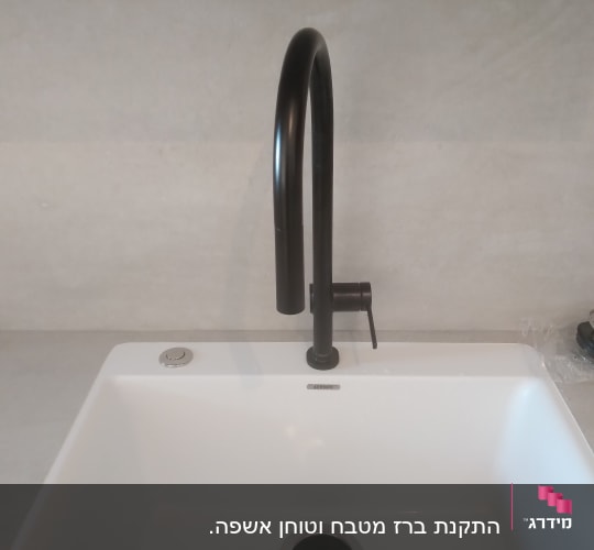 ברז שחור מעל כיור לבן במטבח